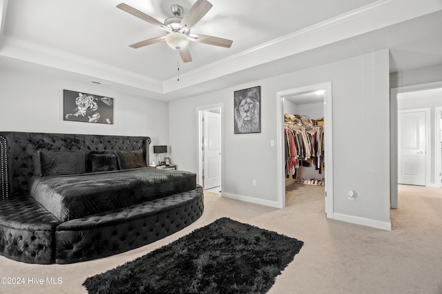 bedroom featuring light carpet, a spacious closet, ceiling fan, and crown molding