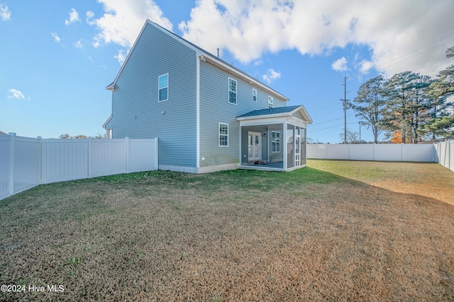 back of house featuring a lawn and a sunroom