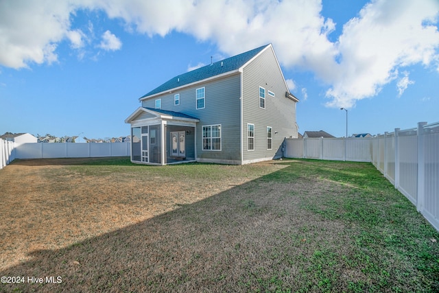 back of property with a yard and a sunroom