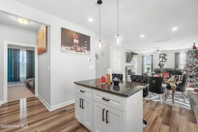 kitchen featuring dark hardwood / wood-style flooring, dark stone counters, ceiling fan, pendant lighting, and white cabinetry