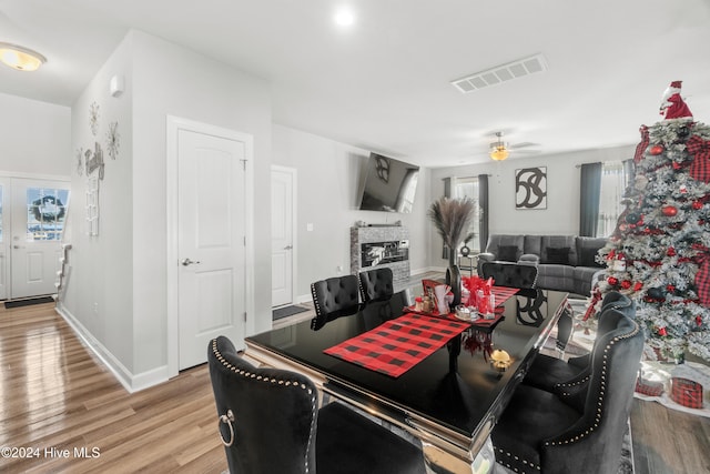 dining space featuring a stone fireplace, ceiling fan, and light hardwood / wood-style flooring