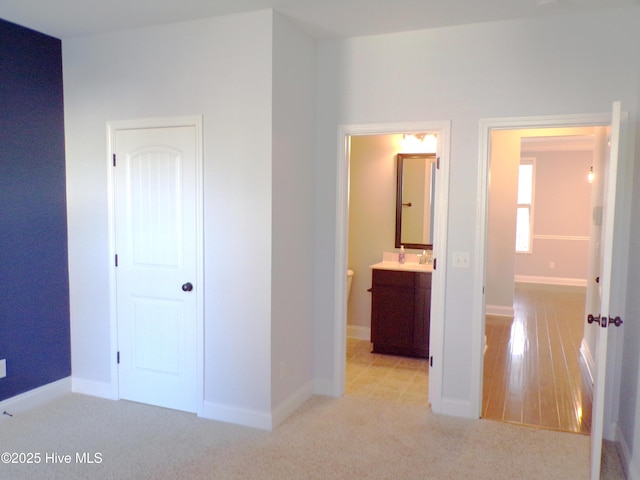 unfurnished bedroom with connected bathroom and light colored carpet