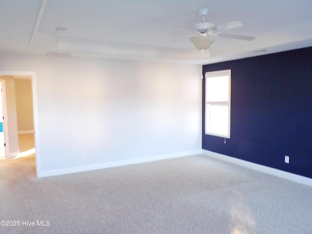 unfurnished room featuring a raised ceiling, ceiling fan, and carpet flooring