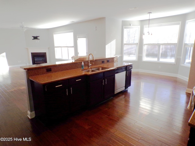 kitchen with sink, stainless steel dishwasher, an island with sink, pendant lighting, and hardwood / wood-style flooring