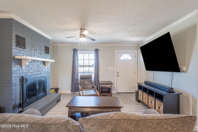 living room featuring a brick fireplace, light hardwood / wood-style flooring, ornamental molding, and a textured ceiling