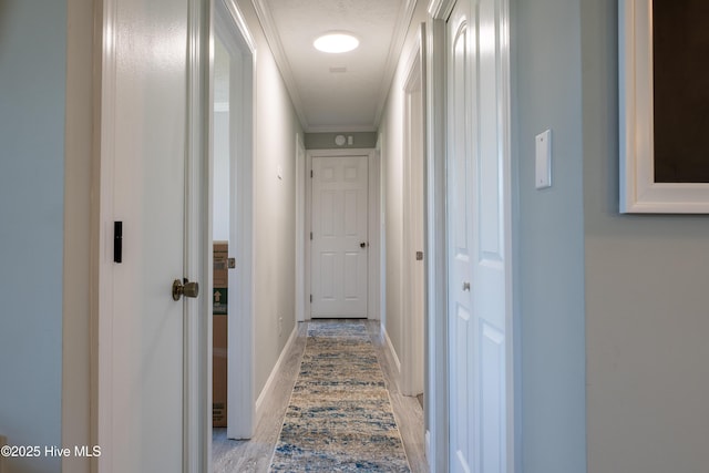 hall featuring ornamental molding, light hardwood / wood-style floors, and a textured ceiling