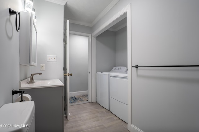 laundry room featuring sink, crown molding, light hardwood / wood-style floors, and washing machine and clothes dryer