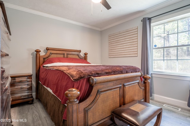 bedroom with ceiling fan, ornamental molding, light hardwood / wood-style flooring, and a textured ceiling