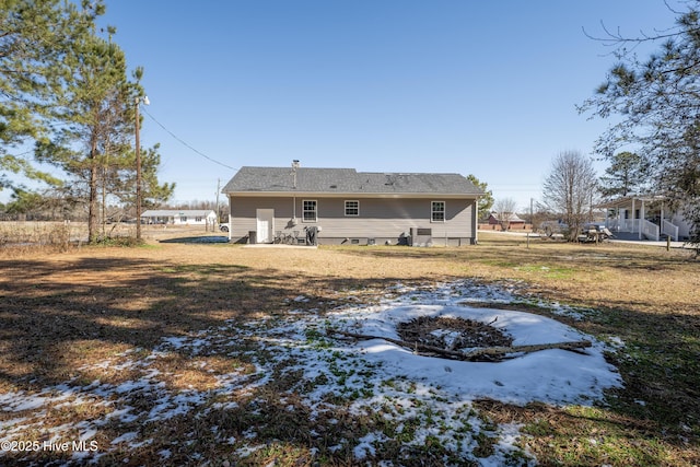 rear view of property featuring a yard and an outdoor fire pit