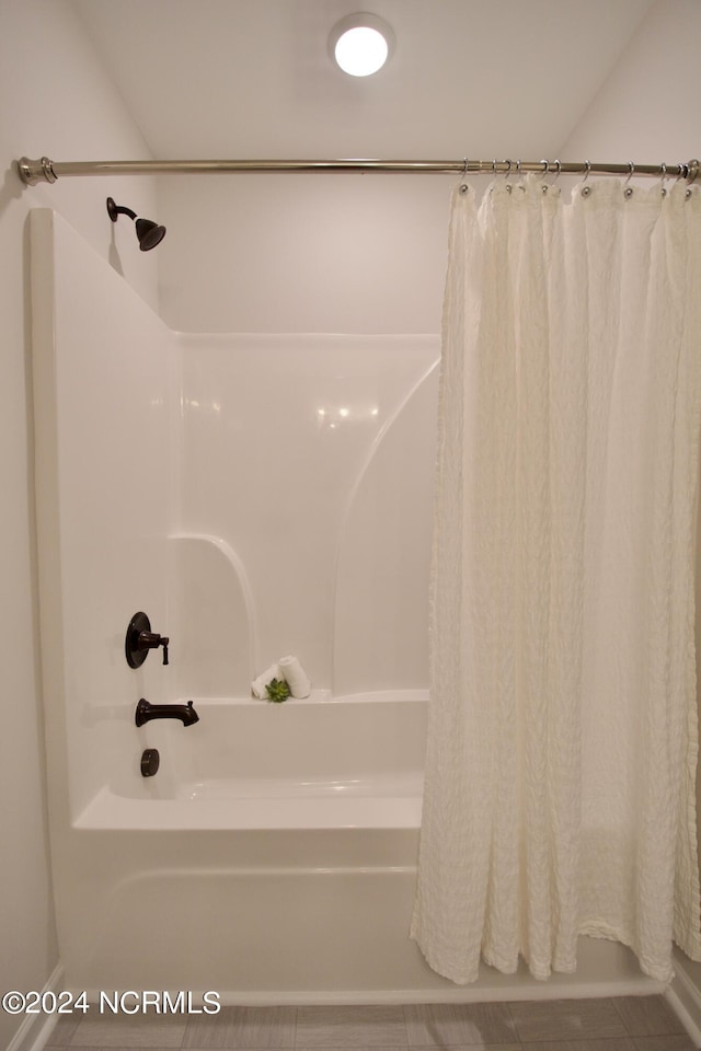 bathroom with tile patterned floors and shower / bath combo with shower curtain