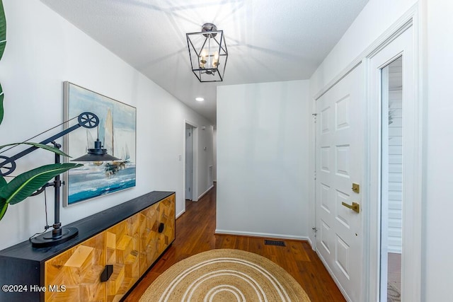 hall with dark hardwood / wood-style floors and an inviting chandelier