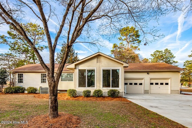 ranch-style home with a front lawn, a garage, and cooling unit