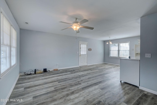 unfurnished living room with ceiling fan with notable chandelier and hardwood / wood-style flooring