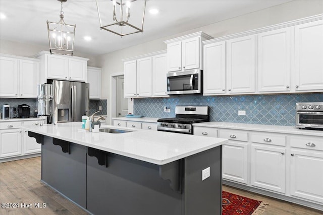 kitchen featuring white cabinetry, appliances with stainless steel finishes, a kitchen island with sink, and sink