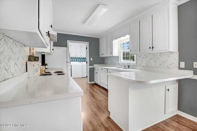 kitchen with kitchen peninsula, light wood-type flooring, white appliances, separate washer and dryer, and white cabinets