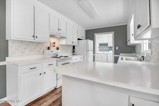 kitchen with white cabinetry, washing machine and dryer, kitchen peninsula, white appliances, and ornamental molding