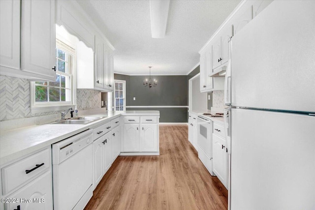 kitchen with white cabinetry, sink, decorative light fixtures, and white appliances