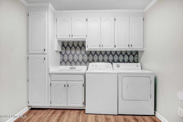 clothes washing area with washer and dryer, light wood-type flooring, crown molding, and sink