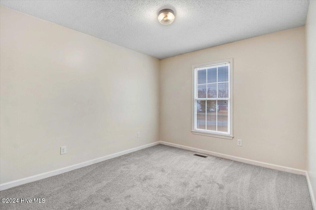 carpeted empty room with a textured ceiling