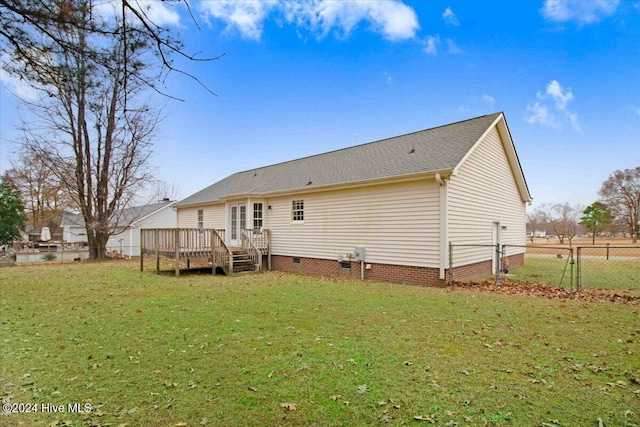 rear view of house with a lawn and a wooden deck