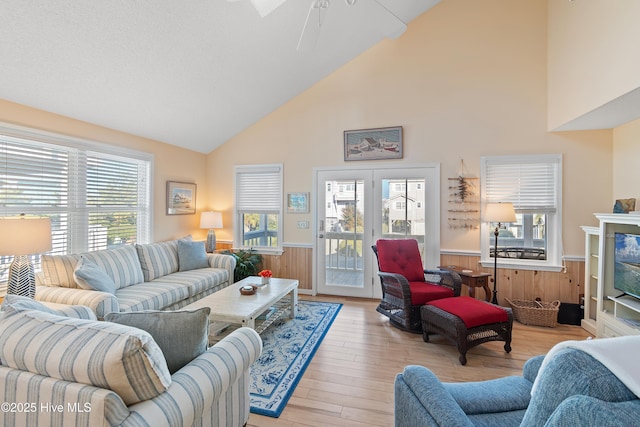 living room featuring wooden walls, light hardwood / wood-style floors, and high vaulted ceiling