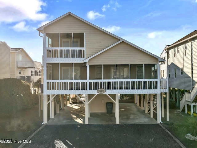 coastal home with a balcony, a carport, and a sunroom