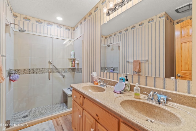 bathroom with a shower with door, vanity, wood-type flooring, and a textured ceiling