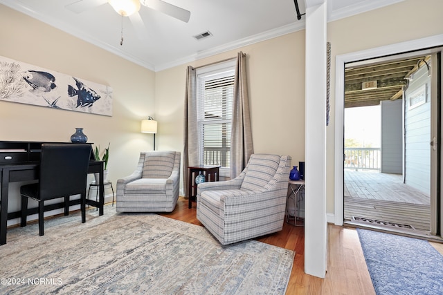 living area featuring hardwood / wood-style floors, crown molding, and ceiling fan