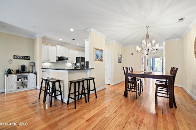 dining space with a notable chandelier, crown molding, and light wood-type flooring