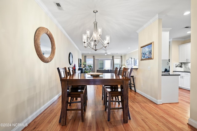 dining space with an inviting chandelier, ornamental molding, and light hardwood / wood-style floors