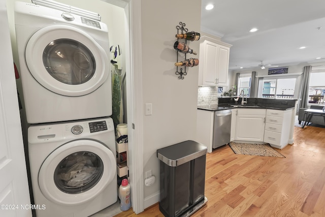 laundry room featuring stacked washer / dryer, light hardwood / wood-style floors, and sink