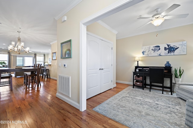 interior space featuring crown molding, wood-type flooring, and ceiling fan with notable chandelier