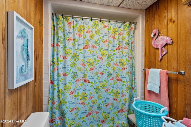 bathroom with curtained shower and wooden walls