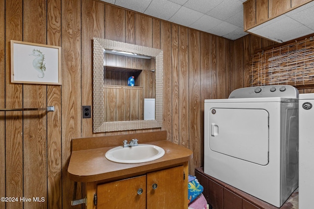 bathroom with vanity, independent washer and dryer, and wooden walls