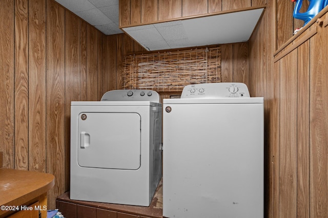 clothes washing area featuring washing machine and clothes dryer and wooden walls