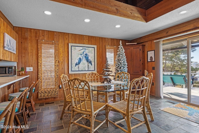 dining area featuring wood walls and a textured ceiling