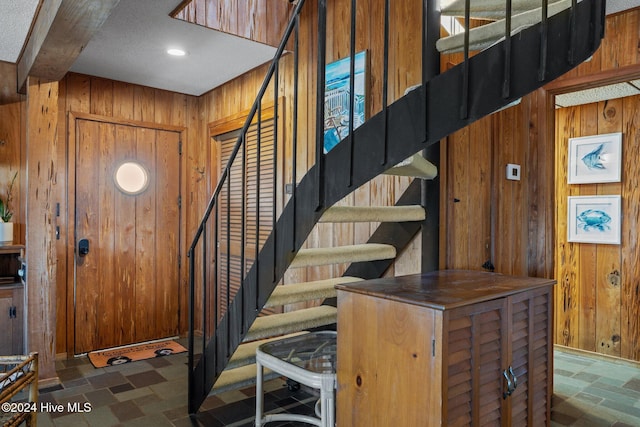 foyer entrance with wood walls and a textured ceiling