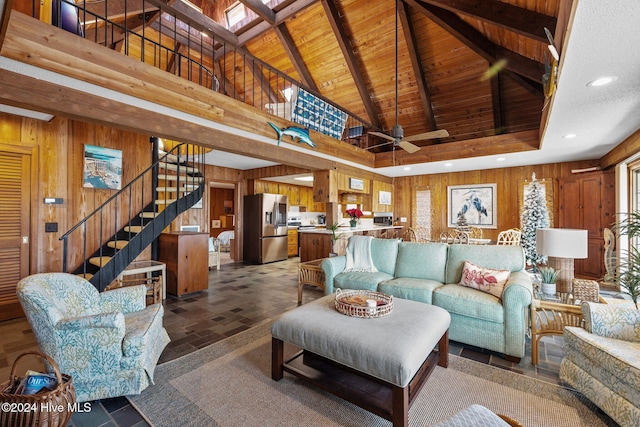 living room featuring ceiling fan, wood walls, beam ceiling, and high vaulted ceiling