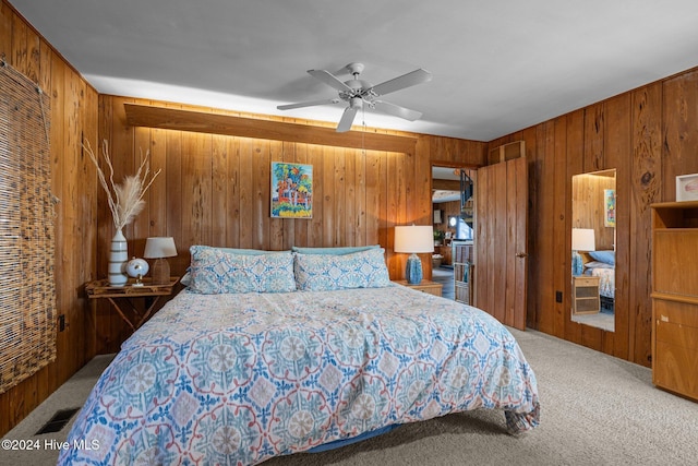 bedroom with ceiling fan, carpet floors, and wood walls