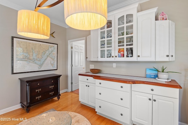 bar featuring white cabinets, light hardwood / wood-style floors, and ornamental molding