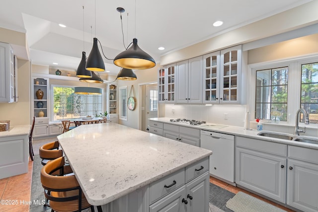 kitchen with tasteful backsplash, white appliances, sink, decorative light fixtures, and a kitchen island