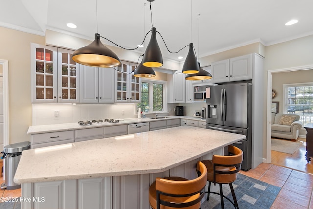 kitchen with pendant lighting, sink, appliances with stainless steel finishes, tasteful backsplash, and a kitchen island