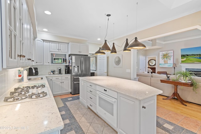 kitchen featuring pendant lighting, a center island, stainless steel appliances, and white cabinetry