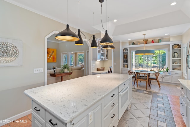 kitchen with pendant lighting, light tile patterned floors, white cabinetry, and a kitchen island