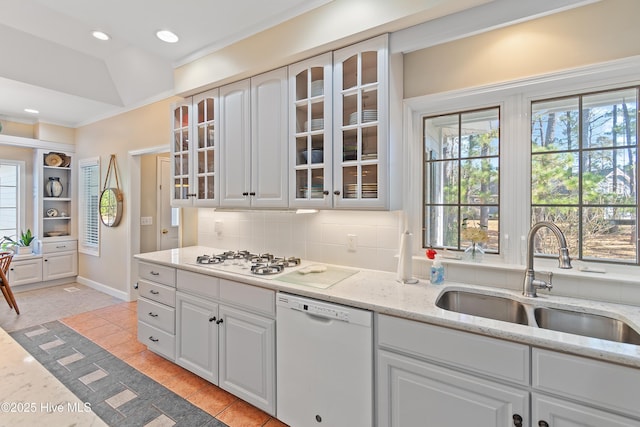 kitchen with light stone countertops, backsplash, white appliances, sink, and white cabinets