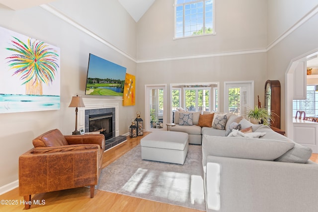 living room featuring a tiled fireplace, a high ceiling, and hardwood / wood-style flooring