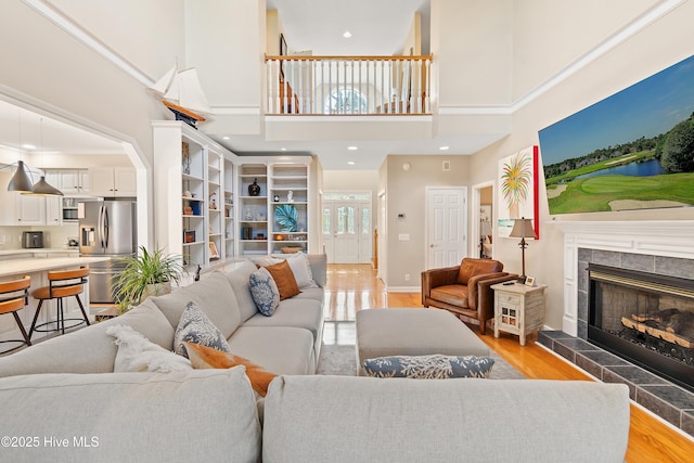 living room with a towering ceiling, a fireplace, and light hardwood / wood-style flooring