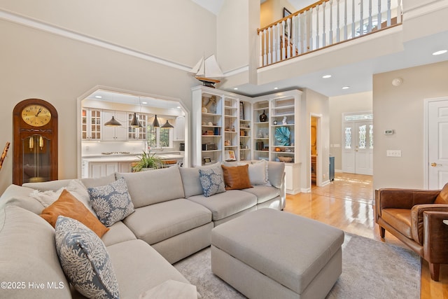 living room featuring a towering ceiling, light hardwood / wood-style floors, and a wealth of natural light