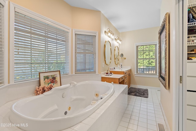 bathroom with tile patterned floors, vanity, and a relaxing tiled tub