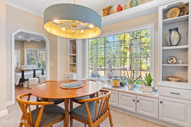 tiled dining room featuring crown molding and ceiling fan with notable chandelier